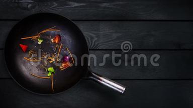 动画。 在黑色木制背景下煎锅中炒面锅的配料